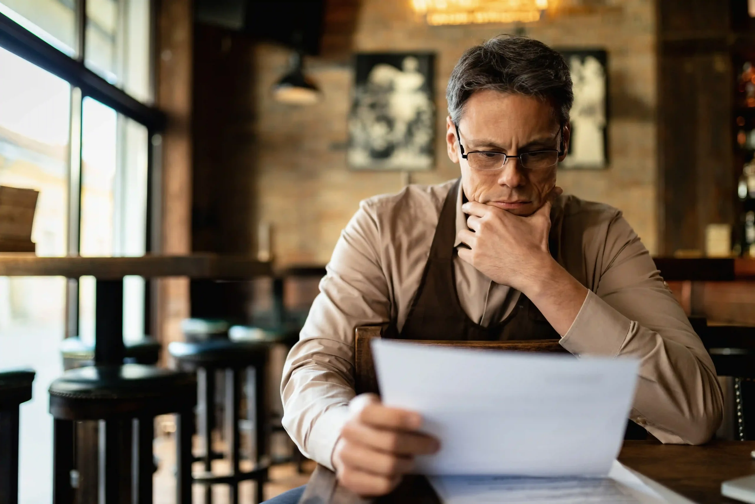 Pensive Cafe Owner Reading Going Through Paperwork Reading Reports After Working Hours 11zon 11zon - ERJ Assessoria Contábil e Tributaria